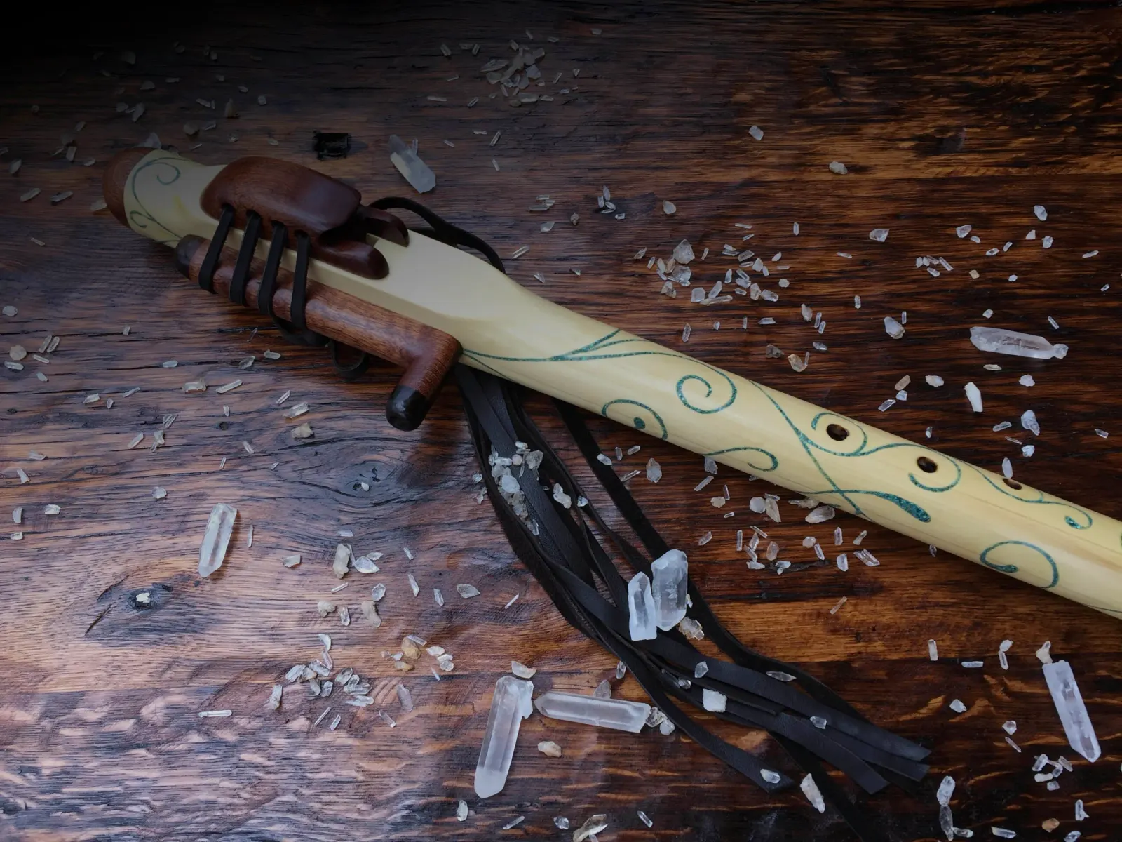 Handmade Native American style drone flute with quartz crystals on a wood table